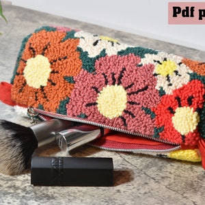 May include: A colourful floral patterned pouch with a zipper opening. The pouch is open and has a makeup brush and lipstick inside.