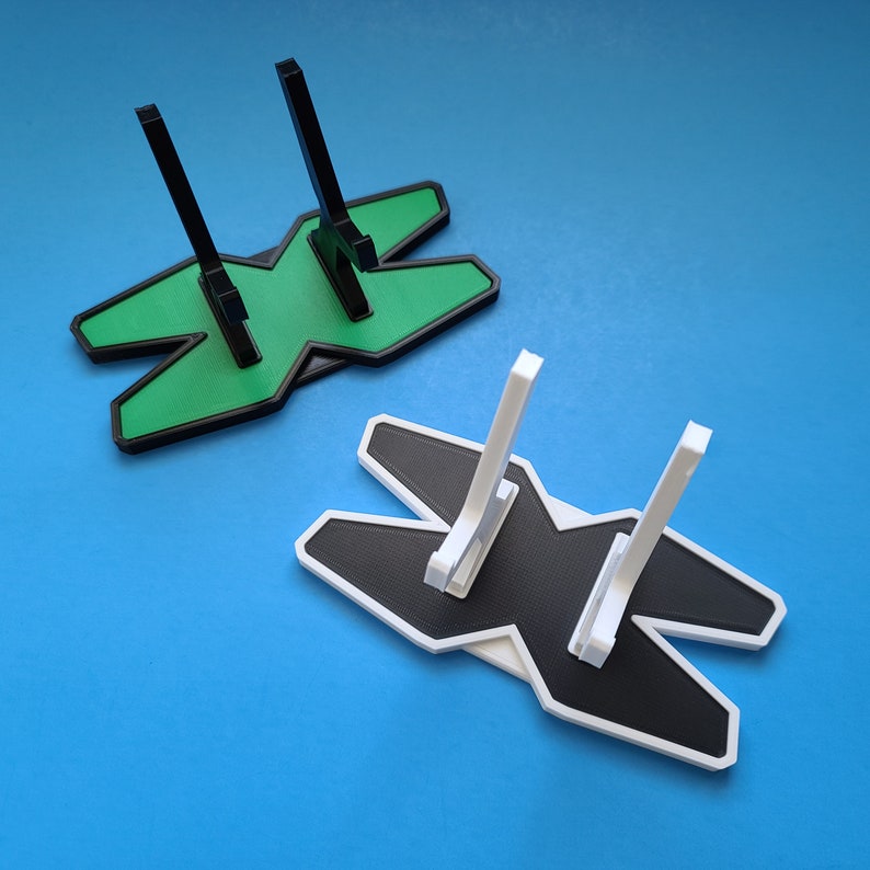 May include: Two 3D printed display stands, one green and one white, shaped like the letter 'X' with two vertical supports.