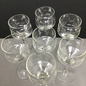 May include: Set of six clear glass wine glasses with etched designs. The glasses have a round bowl and a long stem.