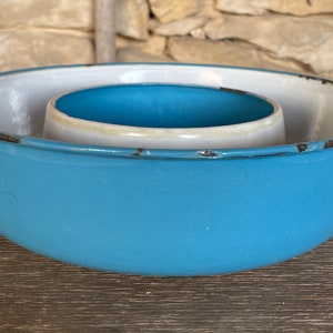 May include: A blue and white enamel cake ring with a handle. The ring has a worn, vintage look.