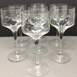 May include: Six clear glass wine glasses with etched designs. The glasses have a tall, slender stem and a wide bowl.