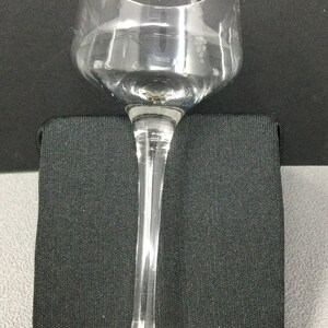 May include: A clear glass wine glass with a long stem and a wide bowl. The glass has an etched design of grapes and vines around the top of the bowl.