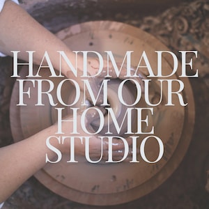 May include: A pair of hands are shaping a lump of clay on a pottery wheel. The text "HANDMADE FROM OUR HOME STUDIO" is superimposed on the image.