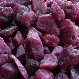 Könnte beinhalten: Nahaufnahme eines Haufens rosa Rubin-Edelsteinchipse. Die Chips sind roh und haben verschiedene Formen und Größen.