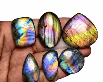 Peut inclure: Six cabochons de labradorite irisés de différentes formes et tailles. Les pierres ont une base gris foncé avec des reflets bleus, verts et dorés.