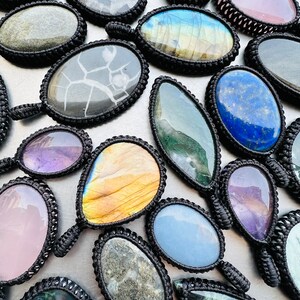 Peut inclure: Assortiment de pendentifs en pierres pr&eacute;cieuses color&eacute;es avec cordon noir, pr&eacute;sentant diverses formes et motifs, notamment une goutte, un ovale et un rond.