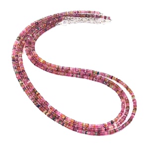 Può includere: Una collana a più fili composta da piccole perline di tormalina sfaccettate a forma di rondella in varie tonalità di rosa, magenta e rosso intenso, dotata di una chiusura a moschettone in metallo argentato e una catenella di estensione.