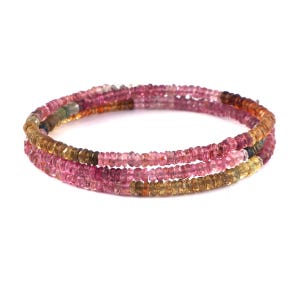 Puede incluir: Una pulsera de múltiples hilos compuesta por pequeñas cuentas circulares facetadas en tonos variados de rosa, ámbar, marrón y amarillo. Las cuentas están ensartadas en un bucle continuo, creando una apariencia en capas con un acabado pulido.