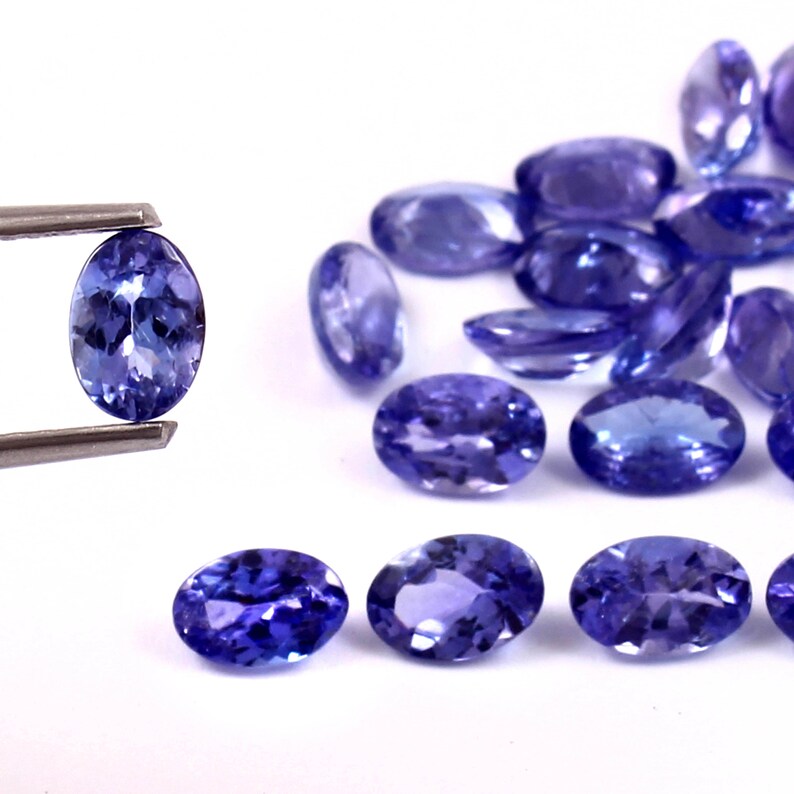 Puede incluir: Un grupo de piedras preciosas azules de forma ovalada y facetadas. Las piedras preciosas est&aacute;n dispuestas en una fila, con la piedra preciosa m&aacute;s grande en el centro. Las piedras preciosas est&aacute;n colocadas sobre un fondo blanco.