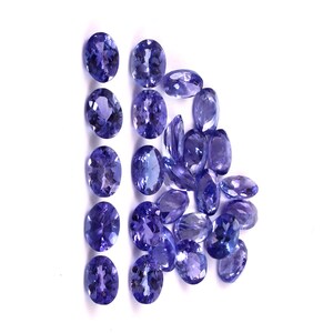 Puede incluir: Una colecci&oacute;n de piedras preciosas ovaladas de color p&uacute;rpura. Las piedras preciosas est&aacute;n dispuestas en una l&iacute;nea y un racimo.
