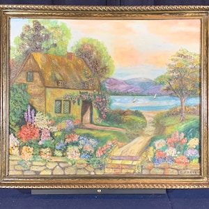 May include: A painting depicting a cottage with a thatched roof, surrounded by flowers and a stone wall. The cottage is situated on a hill overlooking a lake with sailboats in the distance. The sky is a soft orange and pink.