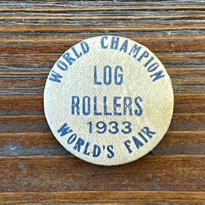 May include: A white button with blue text that reads "World Champion Log Rollers 1933 World's Fair".