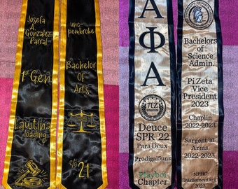 May include: Two black graduation stoles with gold trim and embroidered text. The stoles feature the text "1st Gen", "Lawtina loading", "Bachelor of Arts", and "c/o 21". A gold stole with black trim features the text "APA", "Deuce SPR 22", "Para Deux", "Prodigal5uns", and "Playboi Chapter". A beige stole with black trim features the text "Bachelors of Science Admin", "PiZeta Vice President 2023", "Chaplin 2022-2023", "Sargent at Arms 2022-2023", and "NPHC Parliamentary 2023".