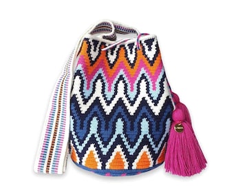 May include: A crochet bucket bag featuring a vibrant zigzag pattern in orange, hot pink, light blue, navy blue, and white. The bag includes a wide, multi-colored woven shoulder strap and a large, bright pink tassel with a small gold charm.