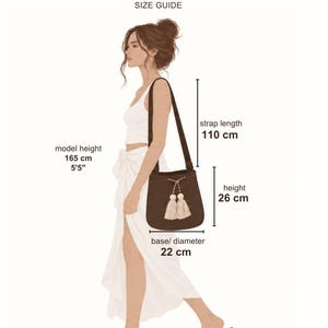 May include: A brown shoulder bag with two cream-colored tassels on the front. The bag has a strap length of 110 cm, a height of 26 cm, and a base diameter of 22 cm. The text Large Bag SIZE GUIDE is at the top, with model height listed as 165 cm or 5'5".