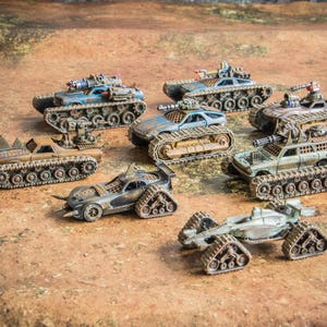 Puede incluir: Una colecci&oacute;n de siete veh&iacute;culos de combate en miniatura postapocal&iacute;pticos con orugas, acabados de pintura desgastados en tonos azul, marr&oacute;n, verde y gris, y armamento montado que incluye ca&ntilde;ones y p&uacute;as sobre diversos dise&ntilde;os de chasis.