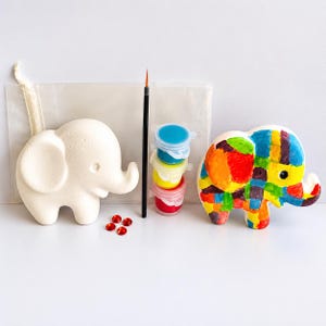 Peut inclure: Un kit de bricolage avec une figurine d'éléphant blanche, des pots de peinture, un pinceau et des ornements de pierres précieuses rouges. Un éléphant est peint avec un motif patchwork coloré. Kit créatif.