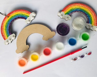 May include: A craft kit with two wooden rainbow shapes, one with glitter and one plain, along with paint pots, glitter, and rhinestones. The kit includes red, orange, yellow, green, blue, white, and purple paint.