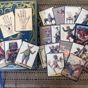 Occult art cards with demon and grimoire illustrations displayed on a journal, ideal for journaling, scrapbooking, and collage projects.