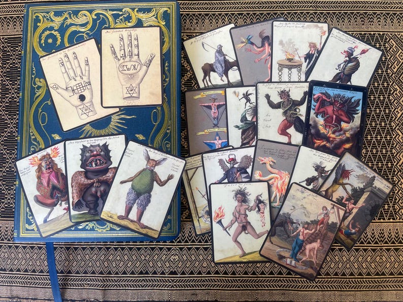 Occult art cards with demon and grimoire illustrations displayed on a journal, ideal for journaling, scrapbooking, and collage projects.