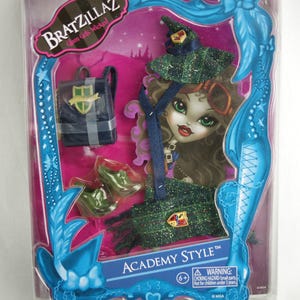Könnte beinhalten: Ein Bratzillaz-Puppenoutfit in einer Plastikverpackung. Das Outfit ist grün und schwarz mit einem Hexenhut, einem Rucksack und Schuhen. Die Verpackung trägt die Aufschrift "Academy Style" und "Glam Gets Wicked".