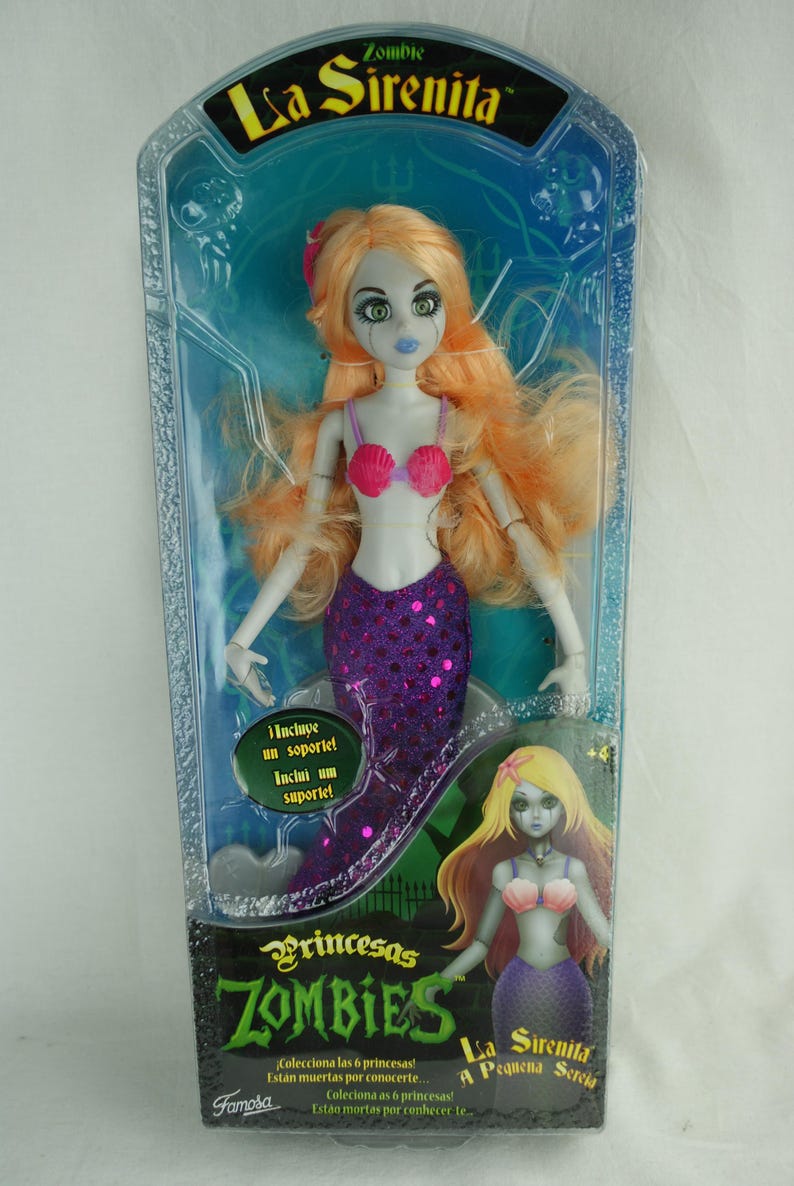 May include: A La Sirenita Zombie doll in original packaging with long orange hair, pale skin, and a purple sequined mermaid tail. The doll wears a pink seashell top. The box features the text La Sirenita, Princesas Zombies, and Famosa.