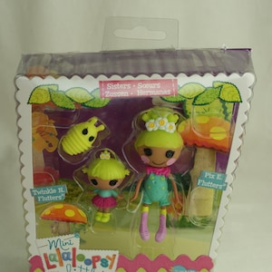 May include: A Lalaloopsy Littles doll set in a clear plastic package. The set includes two dolls, accessories, and the text "Twinkle N. Flutters" and "Pix E. Flutters". The dolls have green hair and colorful outfits.