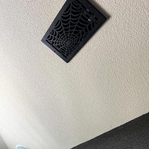 May include: A black ceiling vent with a spiderweb design.