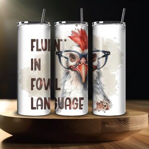 May include: Three white stainless steel tumblers with lids and straws. The tumbler on the left has the text "Fluent in fowl language". The tumbler in the middle has a cartoon chicken wearing glasses. The tumbler on the right has a cartoon chicken wearing glasses.