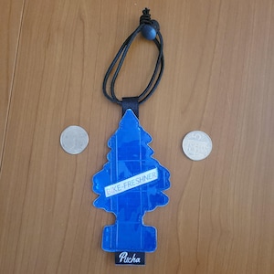 May include: A blue, pine-tree-shaped air freshener with the text "BIKE-FRESHNER" and "Pucha". It has a black cord for hanging. Two coins are on either side of the air freshener.