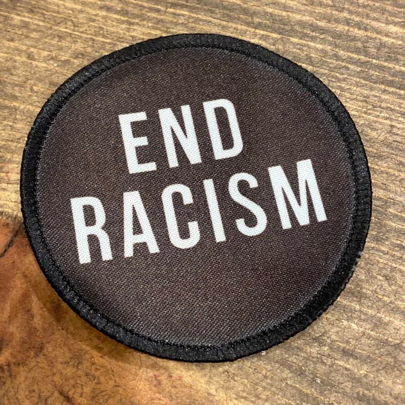 May include: Black round patch with white text that reads "END RACISM".