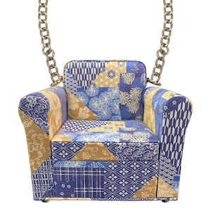 May include: A miniature armchair-shaped handbag with a patchwork design in shades of blue, gold, and white. The bag features a gold chain strap and is designed with a variety of Japanese-inspired patterns. The overall aesthetic is a blend of traditional and modern design.