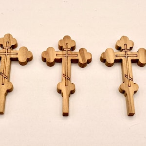 Pode incluir: Tr&ecirc;s cruzes de madeira ortodoxas orientais. Cada cruz apresenta um design de tr&ecirc;s barras: uma barra superior, uma barra do meio e um apoio para os p&eacute;s inclinado. As cruzes s&atilde;o feitas de madeira castanha clara e t&ecirc;m um aspeto esculpido detalhado.
