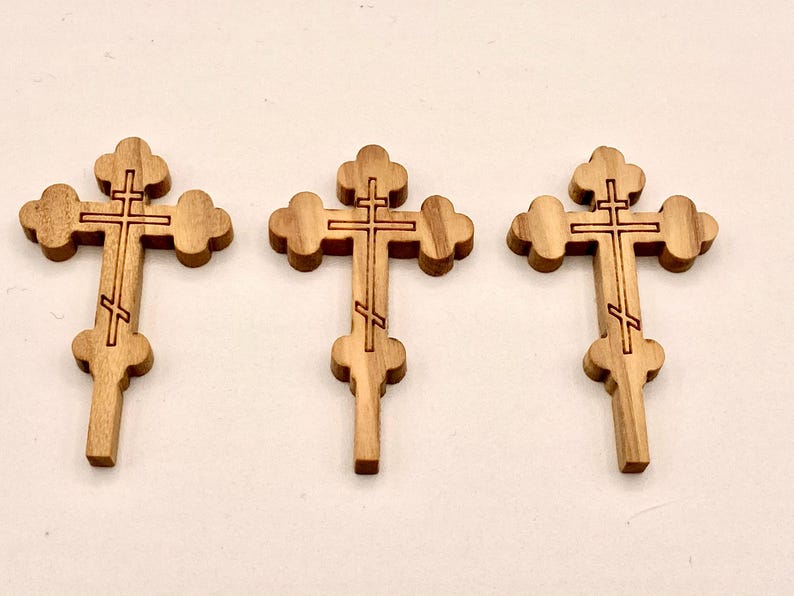 Pode incluir: Tr&ecirc;s cruzes de madeira ortodoxas orientais. Cada cruz apresenta um design de tr&ecirc;s barras: uma barra superior, uma barra do meio e um apoio para os p&eacute;s inclinado. As cruzes s&atilde;o feitas de madeira castanha clara e t&ecirc;m um aspeto esculpido detalhado.