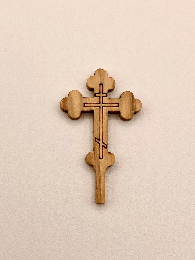 Op de afbeelding: Een houten kruis met een traditioneel orthodox ontwerp. Het kruis is gesneden uit lichtbruin hout en heeft een eenvoudig, elegant ontwerp.