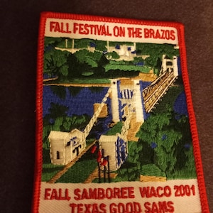 May include: A white and red embroidered patch with the text "Fall Festival on the Brazos Fall Samoree Waco 2001 Texas Good Sams". The patch features a colorful embroidered image of a bridge over a river with trees and buildings in the background.
