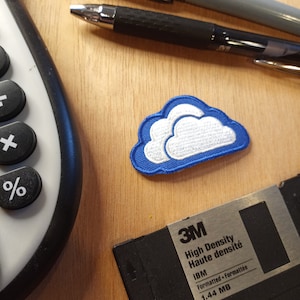May include: A blue and white cloud patch with a 3M floppy disk labeled "High Density Haute densité IBM Formatted Formattée 1.44 MB".