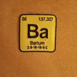 May include: A yellow and black periodic table element patch with the symbol "Ba" for Barium, the atomic number 56, and the atomic weight 137.327. The patch also includes the electron configuration 2-8-18-18-8-2.