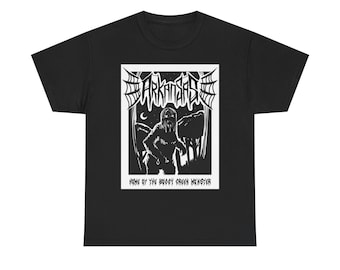 May include: Black t-shirt with a white graphic featuring the word "ARKANSAS" in a stylized font above an illustration of a figure in a forest. The text "HOME OF THE BOGGY CREEK MONSTER" is below the illustration.