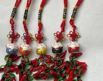 May include: Four red string charms with a lucky cat charm and red and green chili pepper charms. The lucky cat charms are in different colors: blue, orange, yellow, and black.