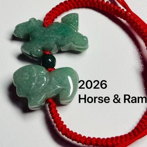 Puede incluir: Colgantes de caballo y carnero de jade verde sobre un cordón rojo. Los colgantes son brillantes. El texto "2026 Horse & Ram" es visible en negro. El cordón tiene cuentas verdes.