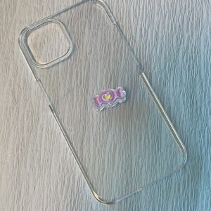 Op de afbeelding: Een transparante telefoonhoes met een roze en gele telefoonhouder in de vorm van een snoepje.