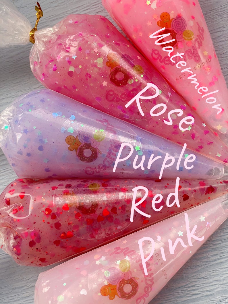 May include: Close-up of five clear plastic bags filled with colorful glitter and liquid. The bags are labeled "Watermelon," "Rose," "Purple," "Red," and "Pink." Each bag features a sticker with a gingerbread man and other sweets.