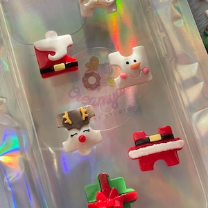 Puede incluir: Seis piezas de rompecabezas con temática navideña hechas de arcilla polimérica. Las piezas representan a Papá Noel, un muñeco de nieve, un reno, una caja de regalo y dos figuras de Papá Noel. Las piezas son blancas, rojas, verdes y marrones.