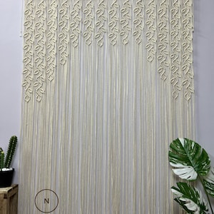 May include: A macrame wall hanging with a leaf pattern. The hanging is made of natural cotton cord and is approximately 70 inches wide and 40 inches tall. The hanging is attached to a wooden dowel rod.