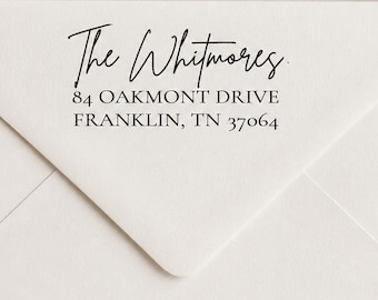 May include: A white envelope featuring a black ink stamp with the text The Whitmores, 84 OAKMONT DRIVE, FRANKLIN, TN 37064. The stamp uses a combination of a handwritten script font for the name and a clean serif font for the address details.