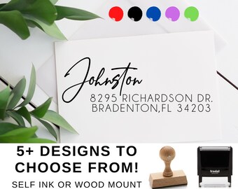 May include: A white card with black text that reads "Johnston 8295 Richardson Dr. Bradenton, FL 34203". The text is in a handwritten font. Below the text is a black and white image of a self-inking stamp and a wood-mounted stamp. The text "5+ Designs to Choose From! Self Ink or Wood Mount" is below the stamps.
