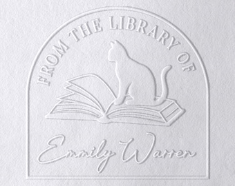 May include: White embossed design featuring a cat silhouette atop an open book, with the text "FROM THE LIBRARY OF" arched above and "Emily Warren" below. The design is on a textured white surface, suggesting a bookplate or stamp.