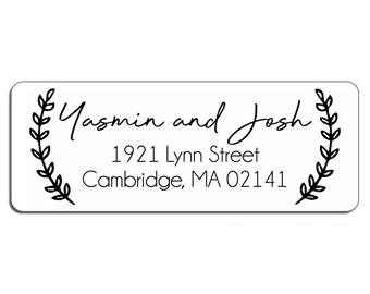 May include: A white return address label with black text and a simple wreath design. The text reads "Yasmin and Josh", "1921 Lynn Street", and "Cambridge, MA 02141".