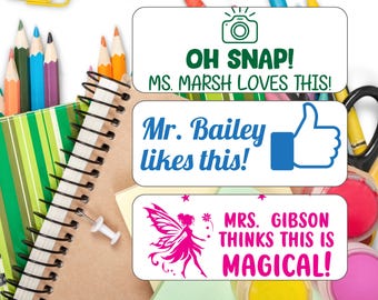 May include: Three colorful teacher appreciation stickers with different designs. The first sticker has a camera icon and the text "OH SNAP! MS. MARSH LOVES THIS!" The second sticker has a thumbs up icon and the text "Mr. Bailey likes this!" The third sticker has a pink fairy icon and the text "MRS. GIBSON THINKS THIS IS MAGICAL!"